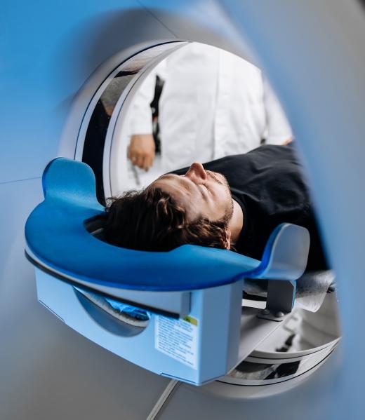 A person lies on their back inside an MRI machine, preparing for a scan. A medical professional stands nearby, partially visible through the scanner opening, highlighting the advanced cardiac imaging services UK patients can access. A person lies on their back inside an MRI machine, preparing for a scan. A medical professional stands nearby, partially visible through the scanner opening, highlighting the advanced cardiac imaging services UK patients can access.